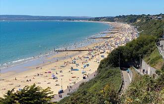 Over cliff shot of middle chine beach in Bournemouth, filled with visitors enjoy the sun.
