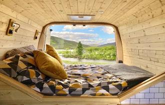 Image of inside a panelled wooden camper looking out to the great outdoors.