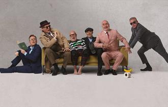 The band Madness sat on a sofa posing for the camera