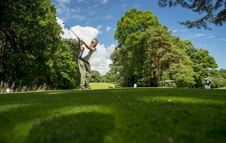 Man winding up his swing before hitting the golf ball on a sunny day