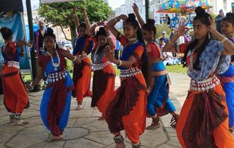 A group of diwali dancers in colourful outfits dancing outside