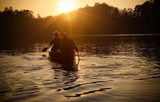 two people in a paddle boat during the sunset