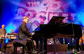image of Elton John impersonator on stage playing piano
