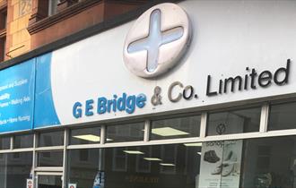 Outdoor signage from the pharmacy that says G E Bridge & Co. Limited.