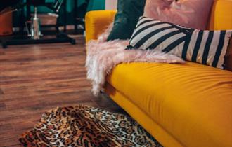 Inside of tattoo studio with yellow sofa and leopard print rug.