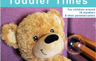 A Toddler Times poster with a brown bear on a purple background with a bubble near his face.