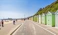 People admiring the beach huts while they walk from Boscombe to Bournemouth pier
