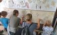 children and adults making art together on a wall.