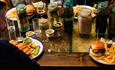 Plates of pub food with table of beer ingredients.