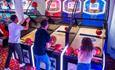 Three people playing a basketball arcade game.