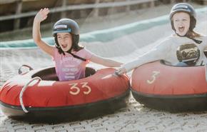 Two girls going down the dry ski slope together on their ringos