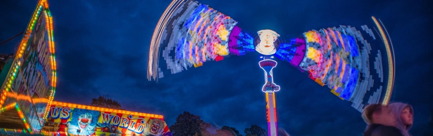 A fairground ride standing tall in the nightsky whilst spinning visitors around