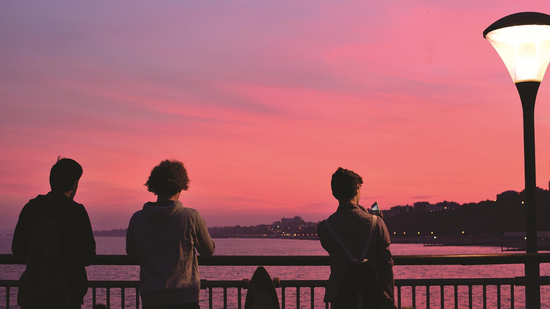 The boys looking at the pink sunset over Bournemout beach