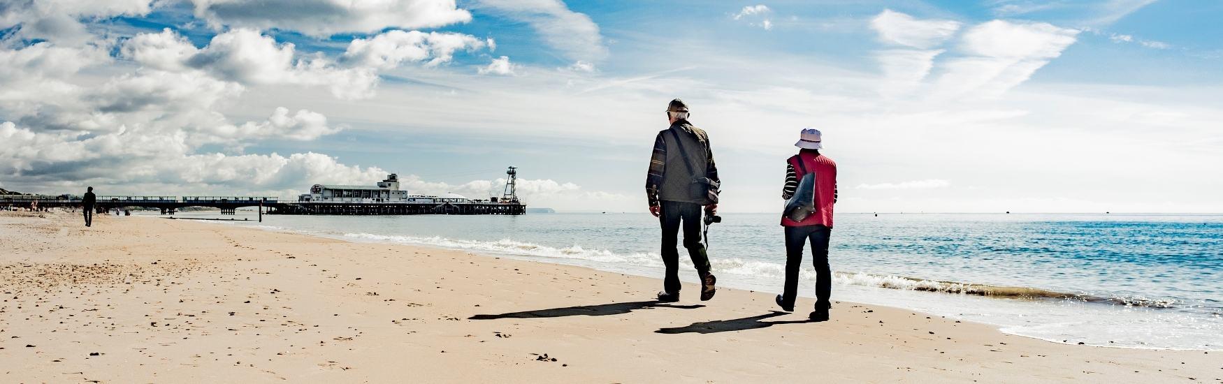 Couple walking along the beach towards Bournemouth pier