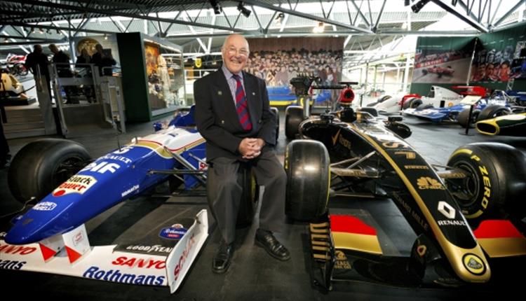 Murray Walker leaning on a racing car