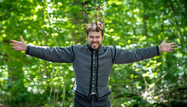 A Christmas Carol actor standing in the woods with his arms out