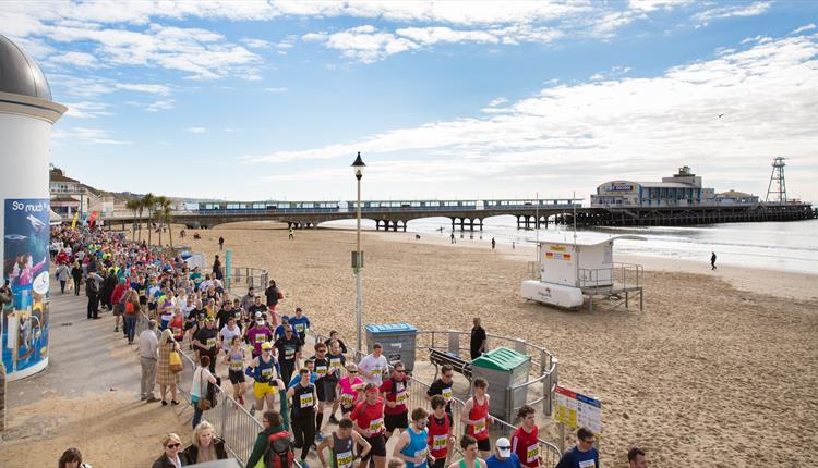 Bournemouth pier on a sunny day with crowds running along the promenade
