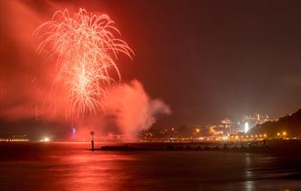 Bournemouth Friday Fireworks with red hue over the pier.
