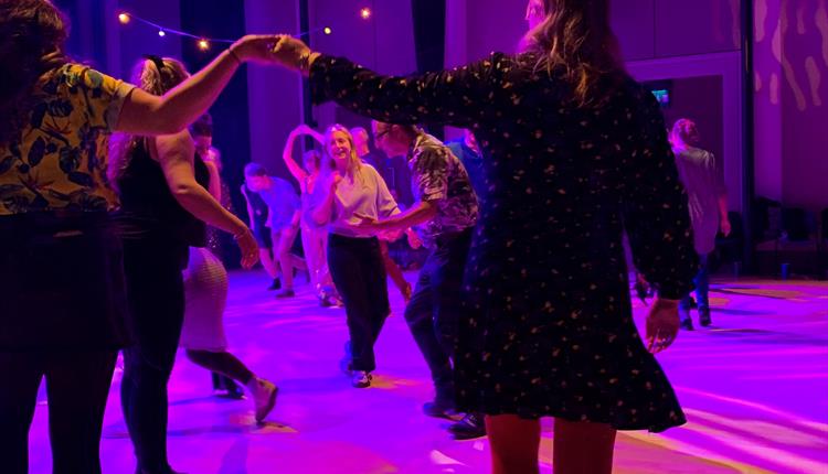 A group of people dancing inside on a dance floor