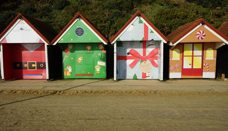 Four of the Christmas beach huts basking in the sun on Bournemouth seafront