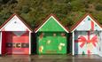 Three Bournemouth beach huts all individual wrapped in a Christmas theme