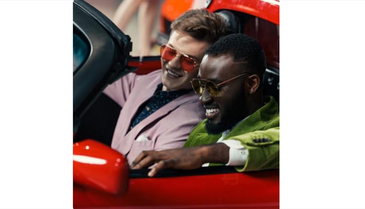 two guys wearing sunglasses smiling in a red car