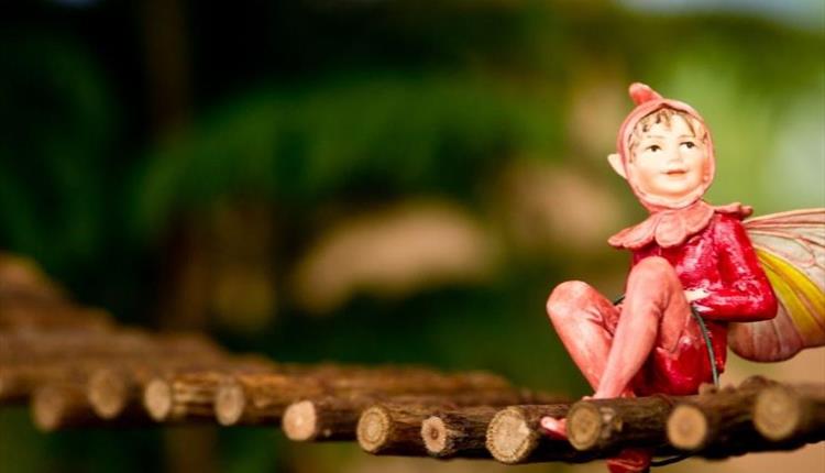 Fairy sitting on a small fairy bridge, gazing into the distance.