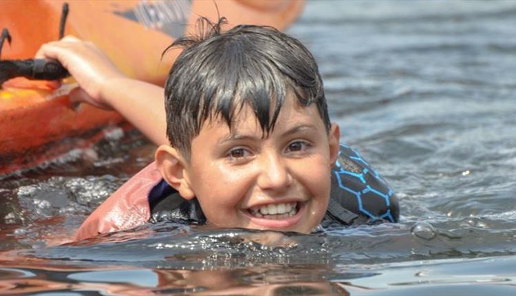 Kid smiling at the camera whilsting swimming