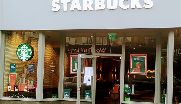 The front of Starbucks in Westbourne with an open door and large grey name above the entrance.