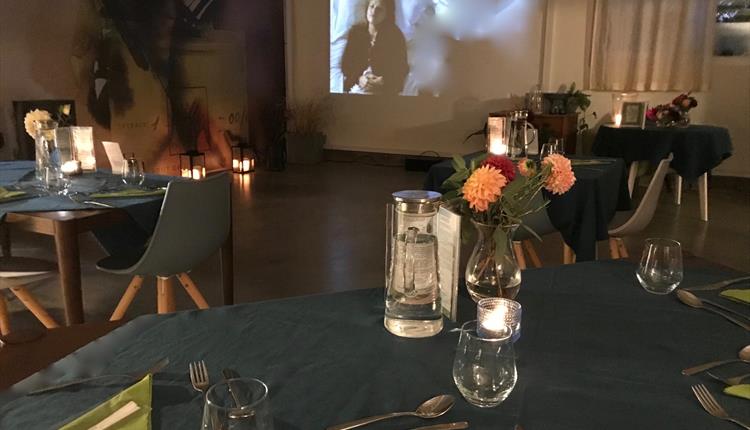 Tables made ready for a dinner in front of the cinema projection screen.