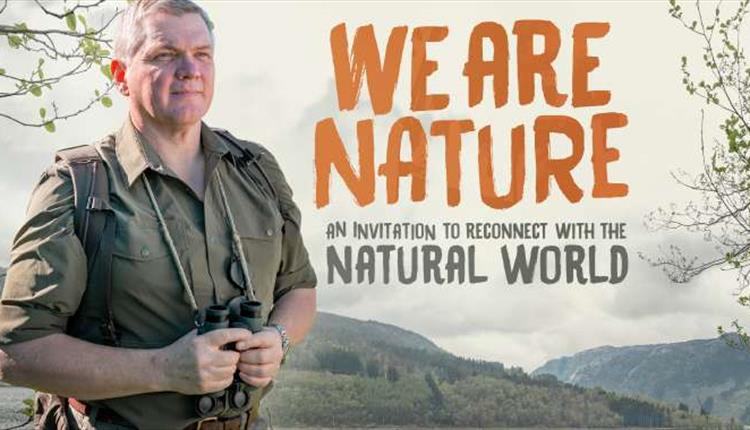 Ray Mears in outdoors gear holding a pair of binoculars