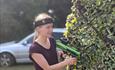 Lady hiding behind a hedge with her laser tag gun