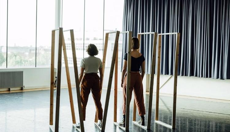 two people dancing in a dance studio looking out to the sea with wooden door frames around them