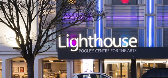 The lighthouse building and logo illuminating the night sky in Poole