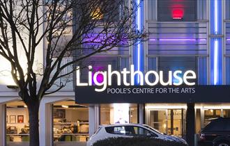 The lighthouse building and logo illuminating the night sky in Poole