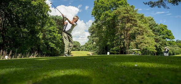 Man winding up his swing before hitting the golf ball on a sunny day