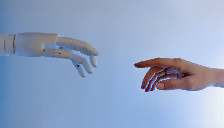 A white robot hand reaching towards a human hand