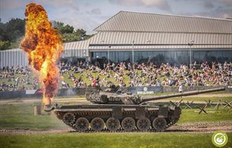 Tank shooting out fire with a crowd of people in the background