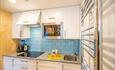 A small but easy accessable kitchen, blue bricked wall with a white mordern cupboard