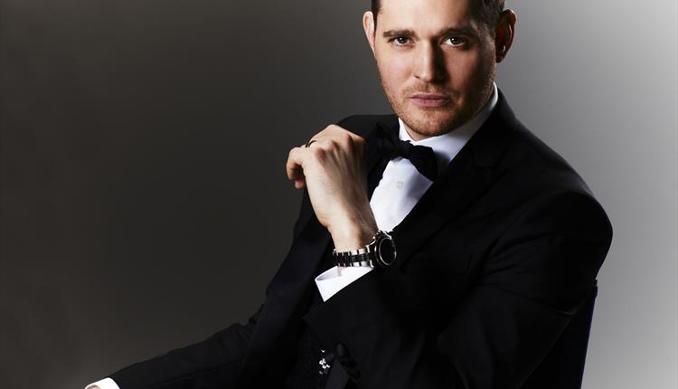 Man dressed in suit and black tie sitting down