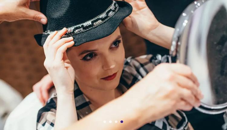 Girl holding a hat looking into the mirror