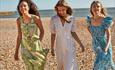Three ladies walking on the beach in summer clothing