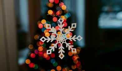 White wooden snowflake decoration lit up by multi-coloured lights