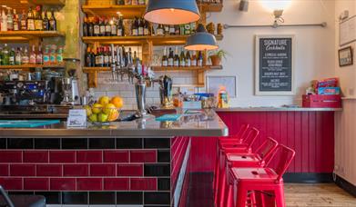 View of the bar with red stools against the bar. 