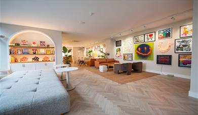 Inside the gallery at Helm, showing comfortable sofas and vibrant artwork int he background