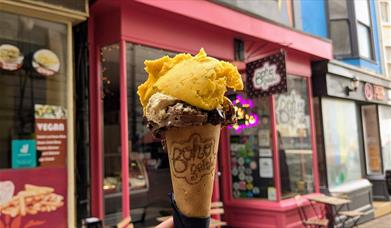 An ice cream cone being held up in front of the Boho Gelato store