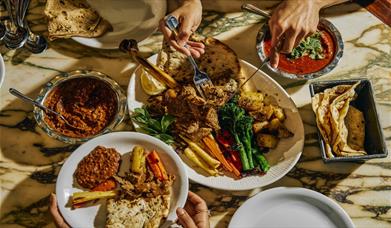 Image shows a range of plates being enjoyed at Dishoom Permit Room Brighton. 