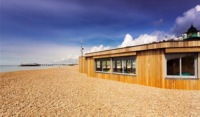 Outside shot of the Yellowave Beach House, a wooden structure with sand outside.