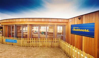 Outside shot of the Yellowave Beach House, a wooden structure with sand outside. 