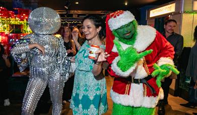 Party goers at Lucky Voice in Brighton dressed up in fancy dress outfits including the Grinch and a dancer wearing disco ball headwear.